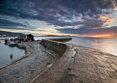 The Cobb at sunrise. The High Wall, the lower walkway and the aquarium can all be seen. The diagonal line running down on the curve of the High Wall is Granny’s Teeth.