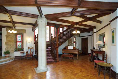 A view of the main hall added by E T Sturdy, showing the splendid staircase, examples of the coloured glass, and some of the furniture acquired by the present owners in keeping with the style of the house