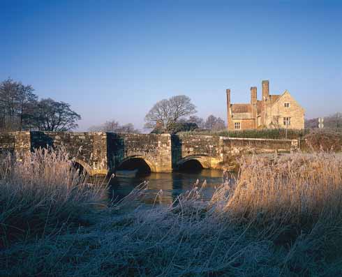 311edTESS4 The Wellbridge Manor of Hardy’s novel, Woolbridge Manor House, shown with the Frome and the Elizabethan stone bridge, parapets somewhat battered by World War 1 tanks, standing in the foreground