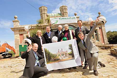 411edDURLSTON02 Before work started: Durlston castle sits behind a jubilant group of contractors and stake-holders in the project holding an artist's impression of the new entrance.