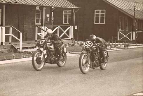511edBLANDFORDpositional1 Two riders rush past the old wooden army huts at Blandford Camp in a 1950s race meeting