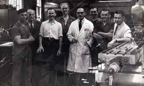 Brian Guy (leaning on lathe) back at work as an engineer after the war