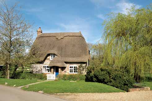 A most attractive brick and flint thatched cottage sits lightly within the rural landscape 