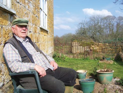 Les relaxes outside the farmhouse he has lived in for over fifty years